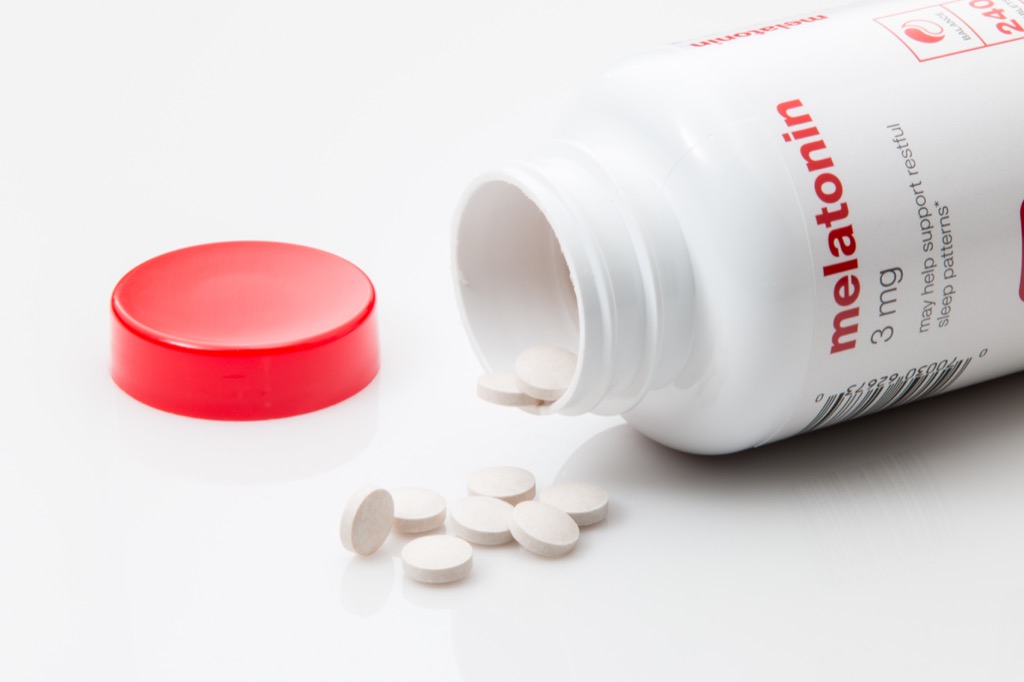 melatonin supplements spilled out of bottle on white background