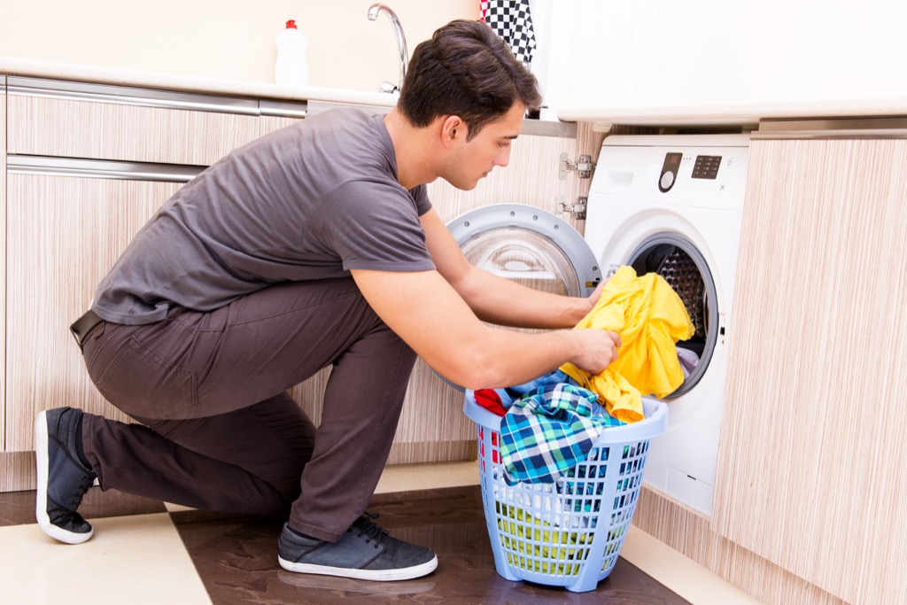 man putting clothes in washing machine laundry folding tips