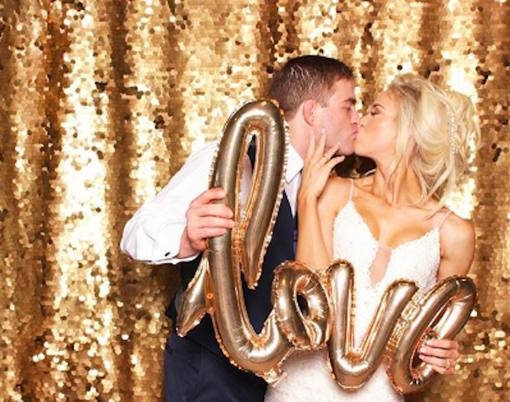 couple holds love balloon while kissing in photo