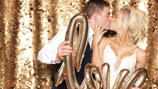 couple holds love balloon while kissing in photo