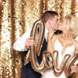 couple holds love balloon while kissing in photo