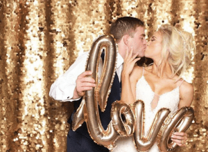 couple holds love balloon while kissing in photo