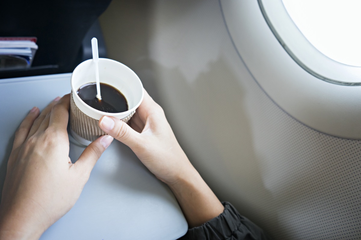 woman holding coffee cup on plane