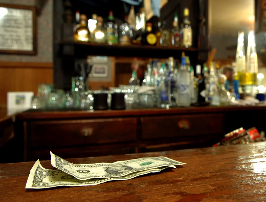 dollar bills sit on top of bar as tip for bartender
