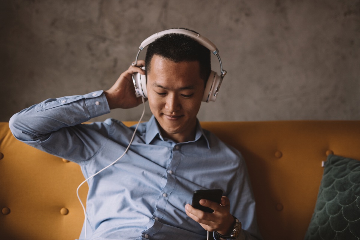 Young Asian man listening to music and relaxing in his office