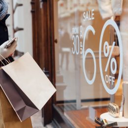Woman shopping and looking at a window marked with a sale