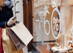 Woman shopping and looking at a window marked with a sale