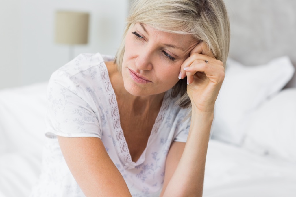 upset woman on bed, midlife crisis signs