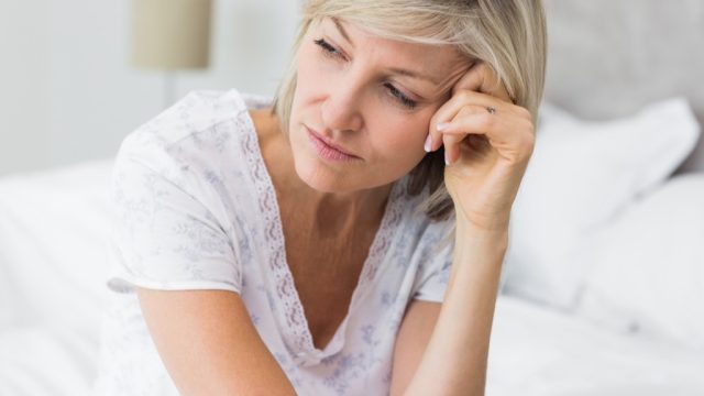upset woman on bed, midlife crisis signs