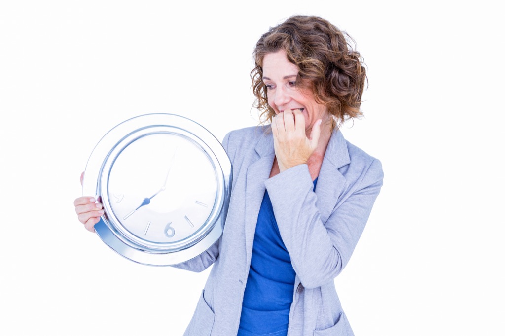 Woman holding clock and looking nervous