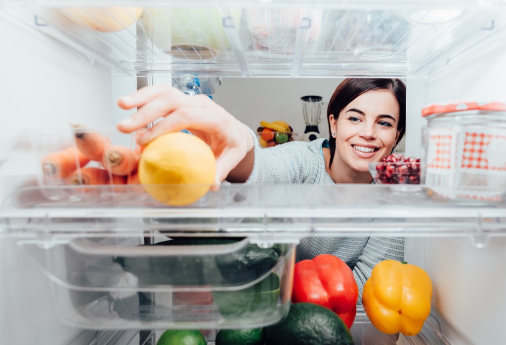 woman reaches for food in the fridge