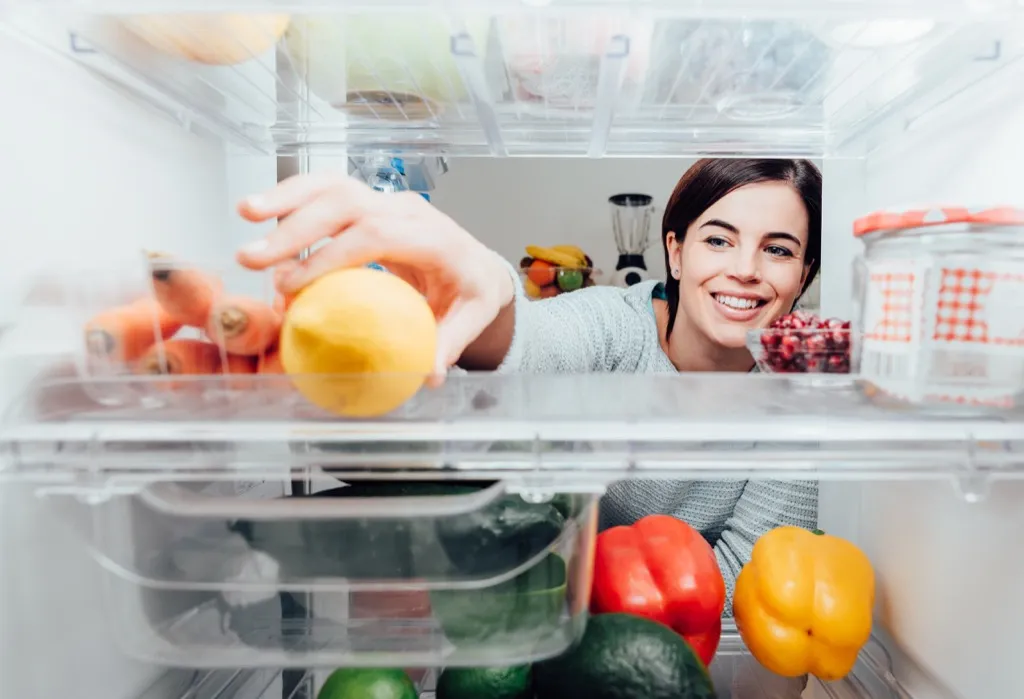 woman reaching for a healthy snack in fridge, weight loss motivation