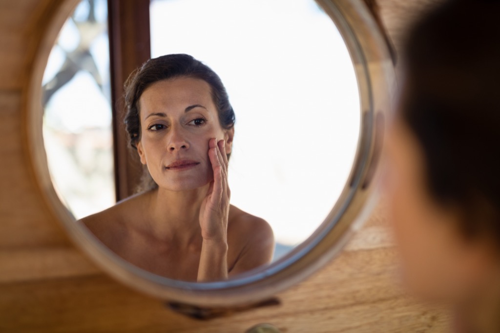 woman looking at her face in the mirror habits after 40