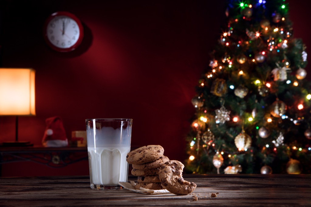 Cookies and milk on a table in front of a Christmas tree