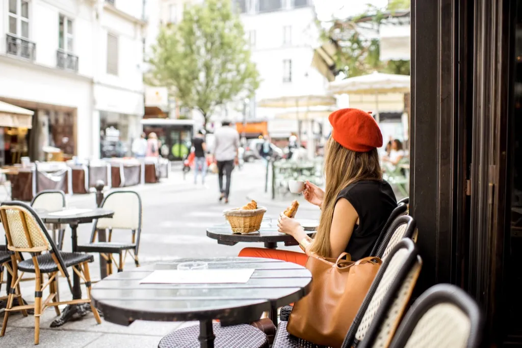 Woman eating croissant in French cafe