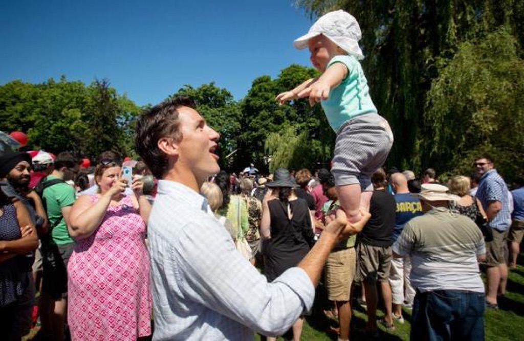 justin trudeau balances baby on one hand.
