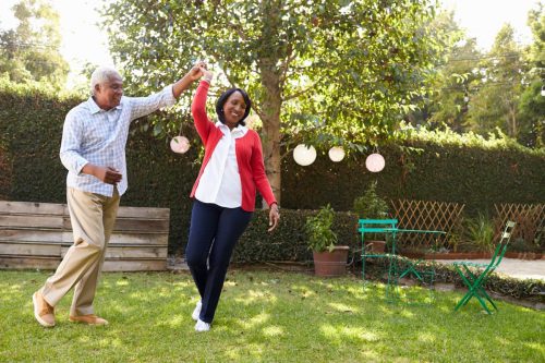Older black couple dancing in backyard