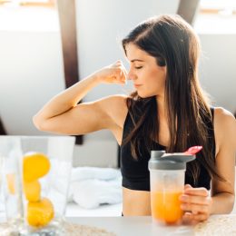 woman drinking juice and making a muscle with bicep