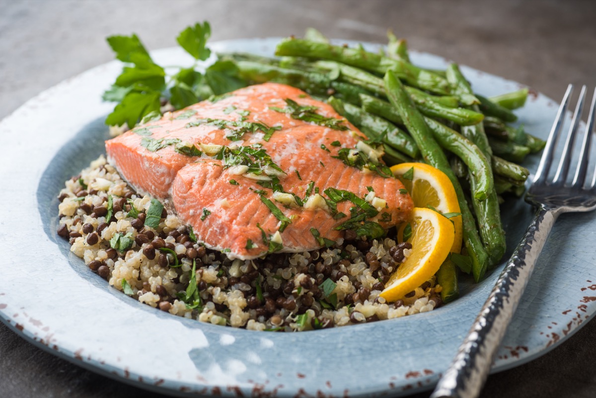 Close up plate of salmon on rice and lentils with green beans