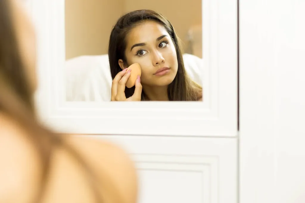 woman putting on makeup in the mirror