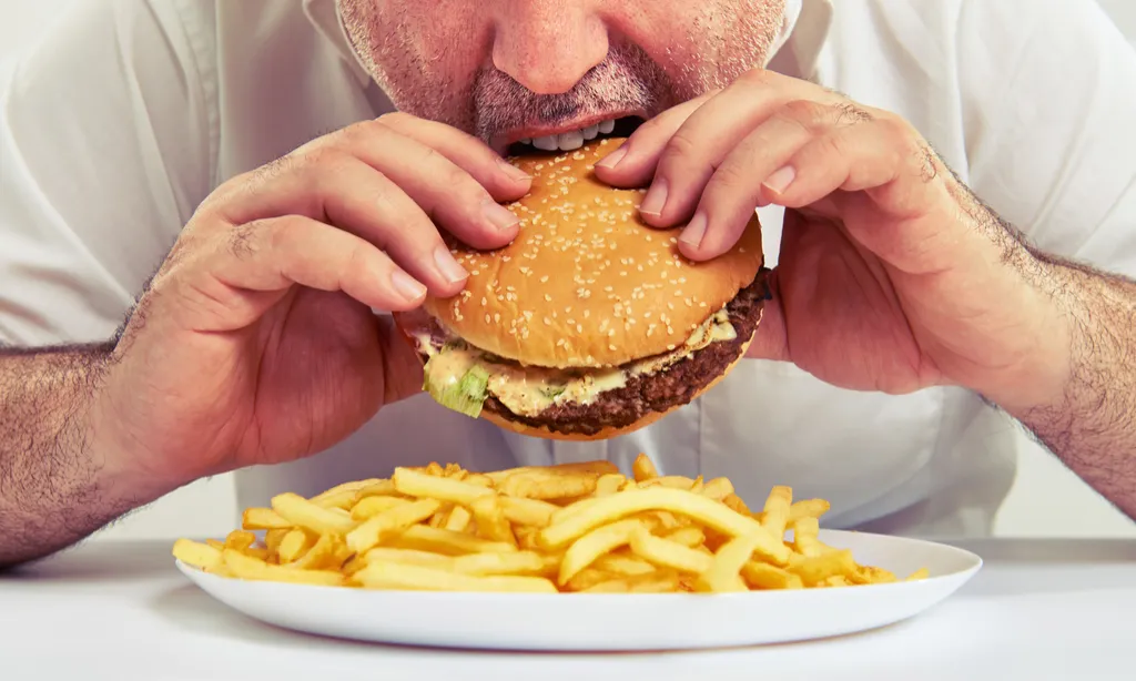 man eating hamburger and french fries