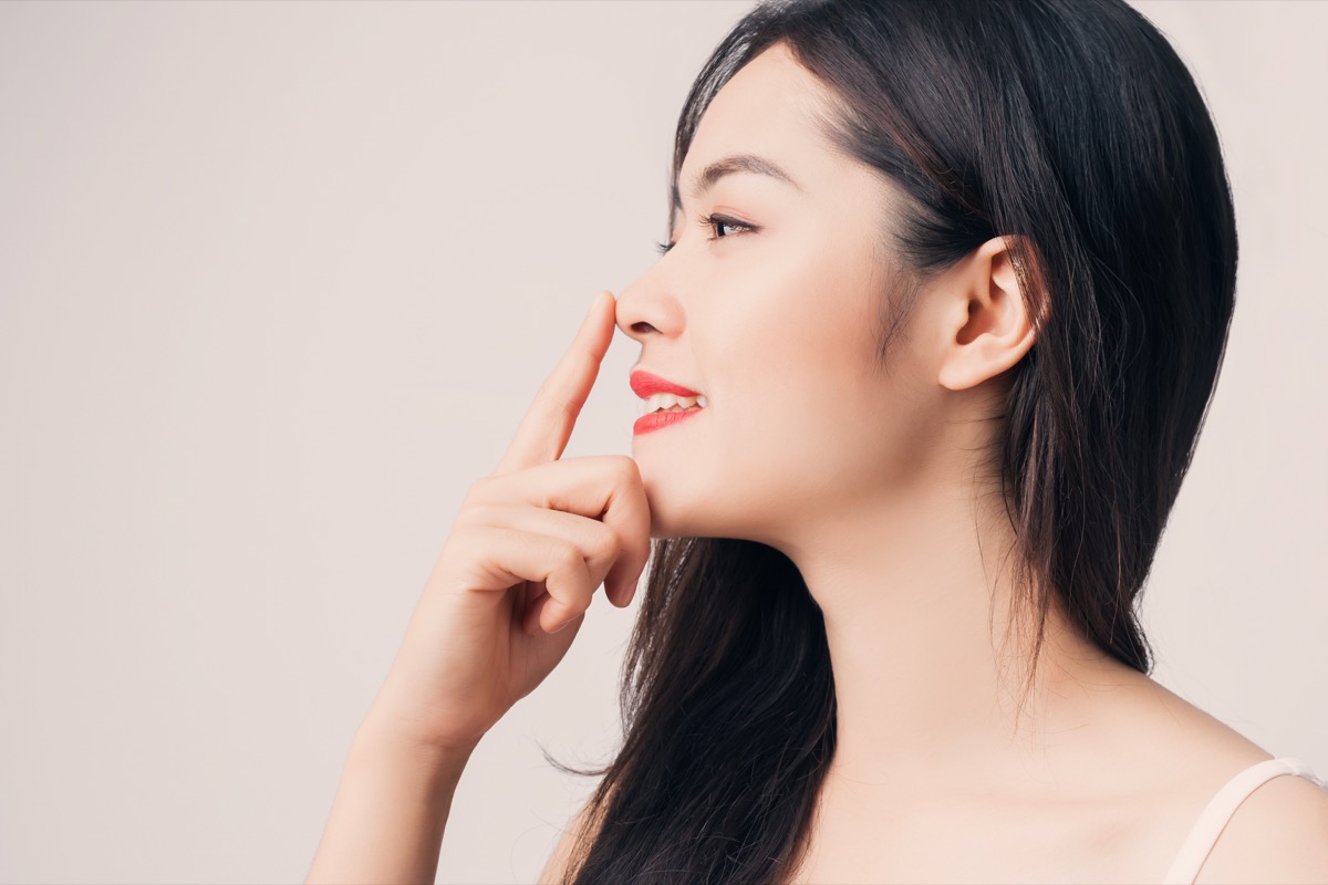 Young beautiful Asian woman with smiley face and red lips touching her nose