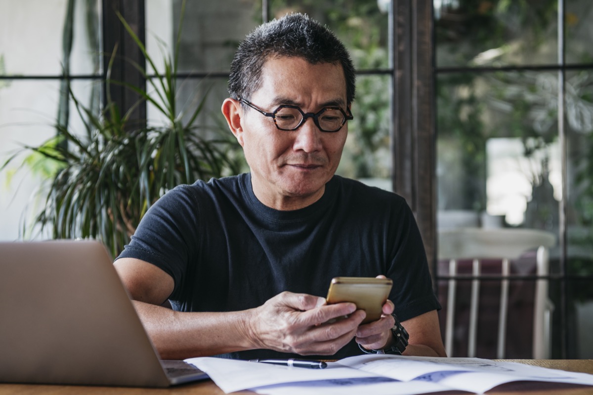 Chinese man in his 50s working remotely, using mobile phone, communication, connections, technology