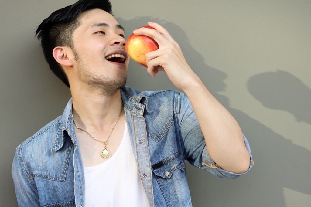 man wearing a jean jacket and eating an apple