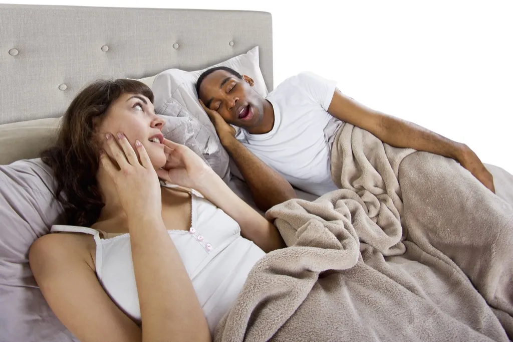 man snoring next to annoyed woman, relationship white lies