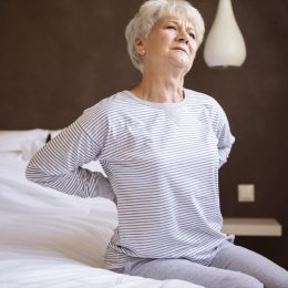 older white woman with back pain in bed