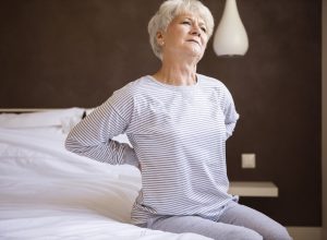 older white woman with back pain in bed