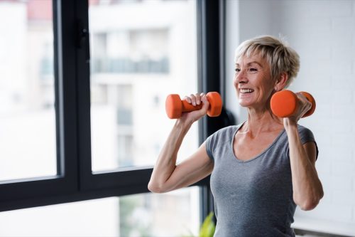 Older woman lifting weights and working out at the gym