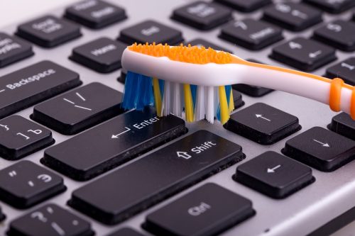 Close-up on toothbrush being used to clean keyboard