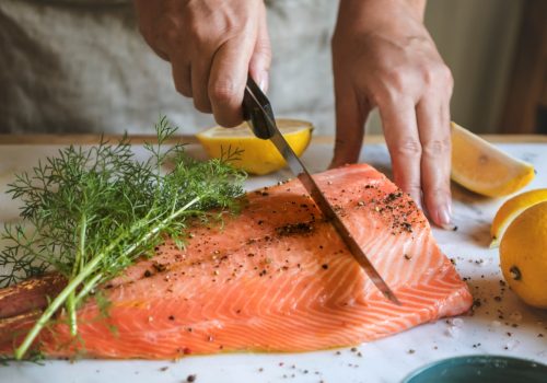 Person preparing a filet of salmon