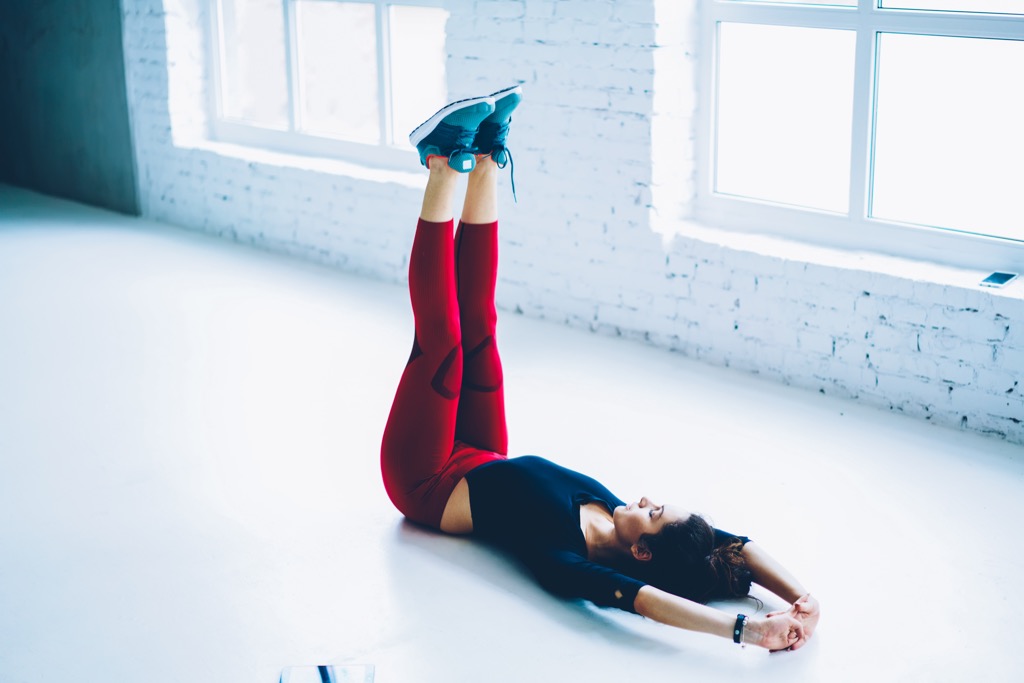 Woman practicing leg raises in white pilates studio