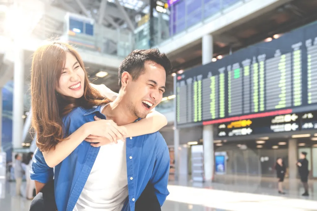 happy couple at airport booking cheap flights