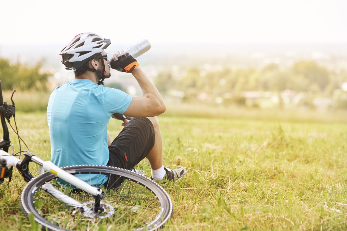 Man drinking from a water bottle with his bike