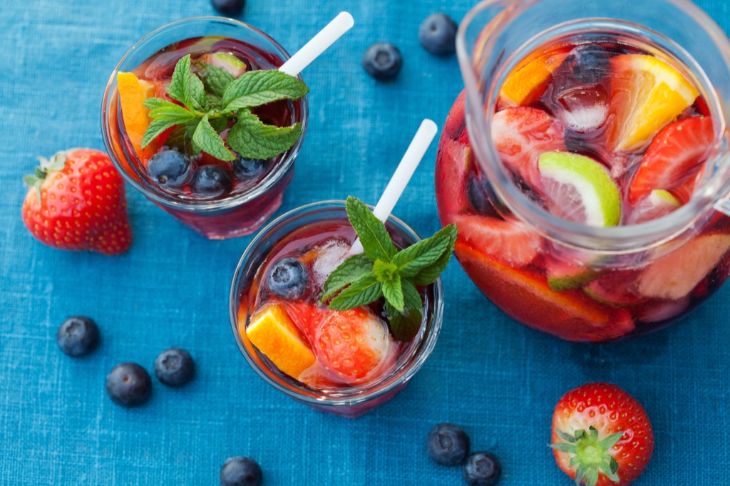 A pitcher of sangria with two glasses, filled with fruit