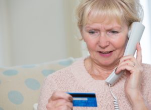 elderly woman giving credit card details by phone.