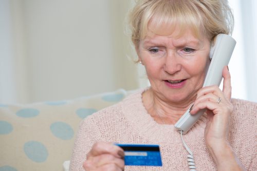 elderly woman giving credit card details by phone.