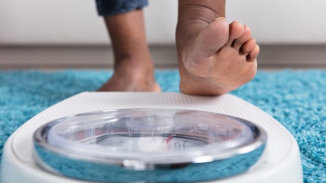 Black woman stepping on a scale to weigh herself
