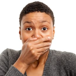 Portrait of a black woman on a white background covering her mouth with her hand