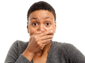 Portrait of a black woman on a white background covering her mouth with her hand