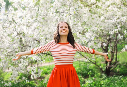 Woman outside walking through flowers and smiling