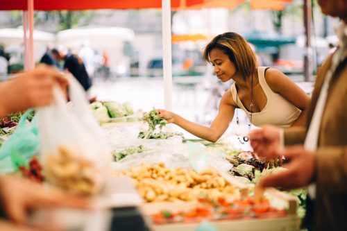 Schwarze Frau kauft Gemüse auf dem Bauernmarkt ein