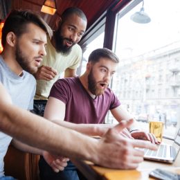 three guys look at a laptop