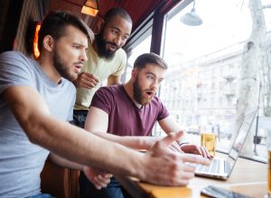 three guys look at a laptop
