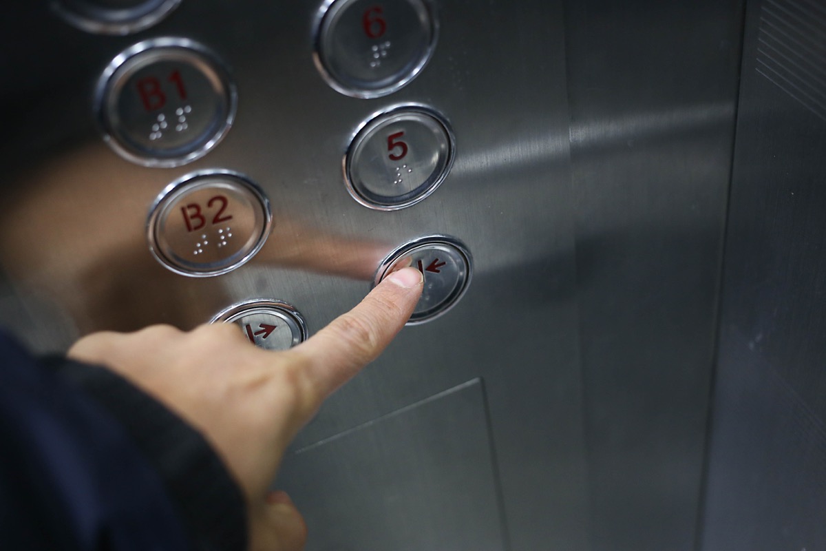 man pressing the elevator close door button