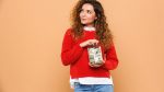 woman holds jar of money and wonders if it makes her an adult.