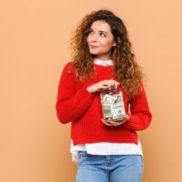 woman holds jar of money and wonders if it makes her an adult.